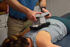 Chris uses electric massager on patient's upper back 